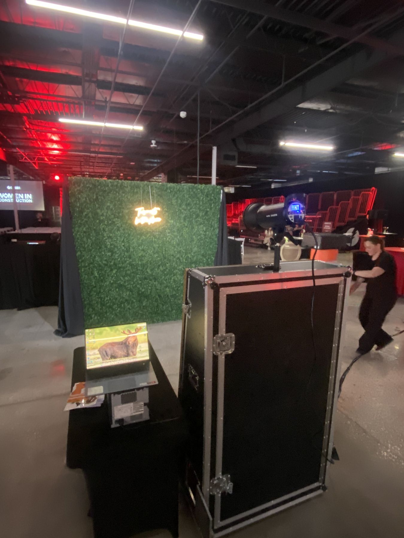 Mirror photo booth with a green hedge wall and a small LED sign at a Tampa event