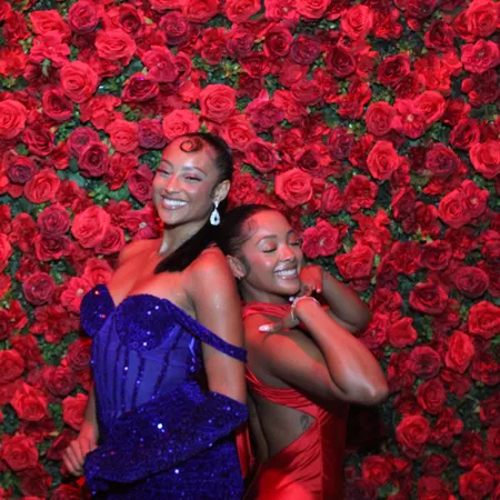 Guests in formal dresses at a Tampa Bay gala with the mirror photo booth and red rose wall
