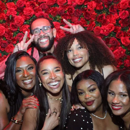 Friends at a Tampa Bay gala mirror photo booth with red rose flower wall