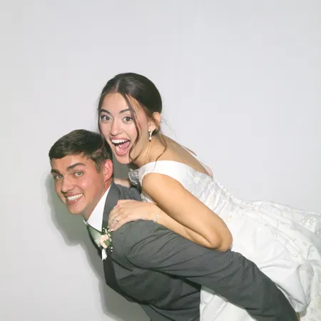 Bride and groom piggyback at the mirror photo booth during a Tampa Bay wedding