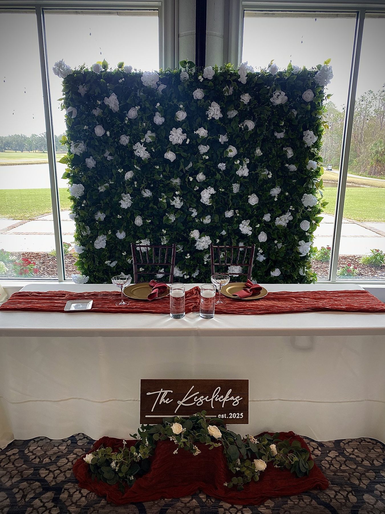 Angel White flower wall behind a sweetheart table set for two, with the couple's wooden sign, at a Tampa wedding