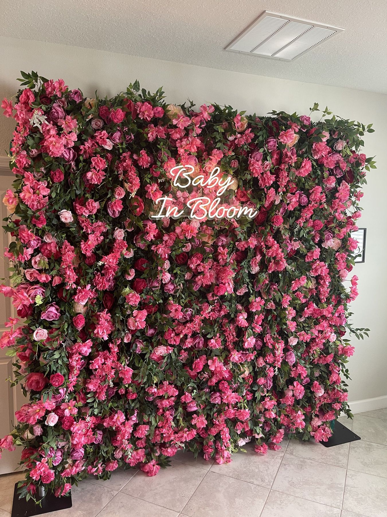 Pink rose flower wall with a Baby In Bloom LED sign fully visible at a Tampa baby shower