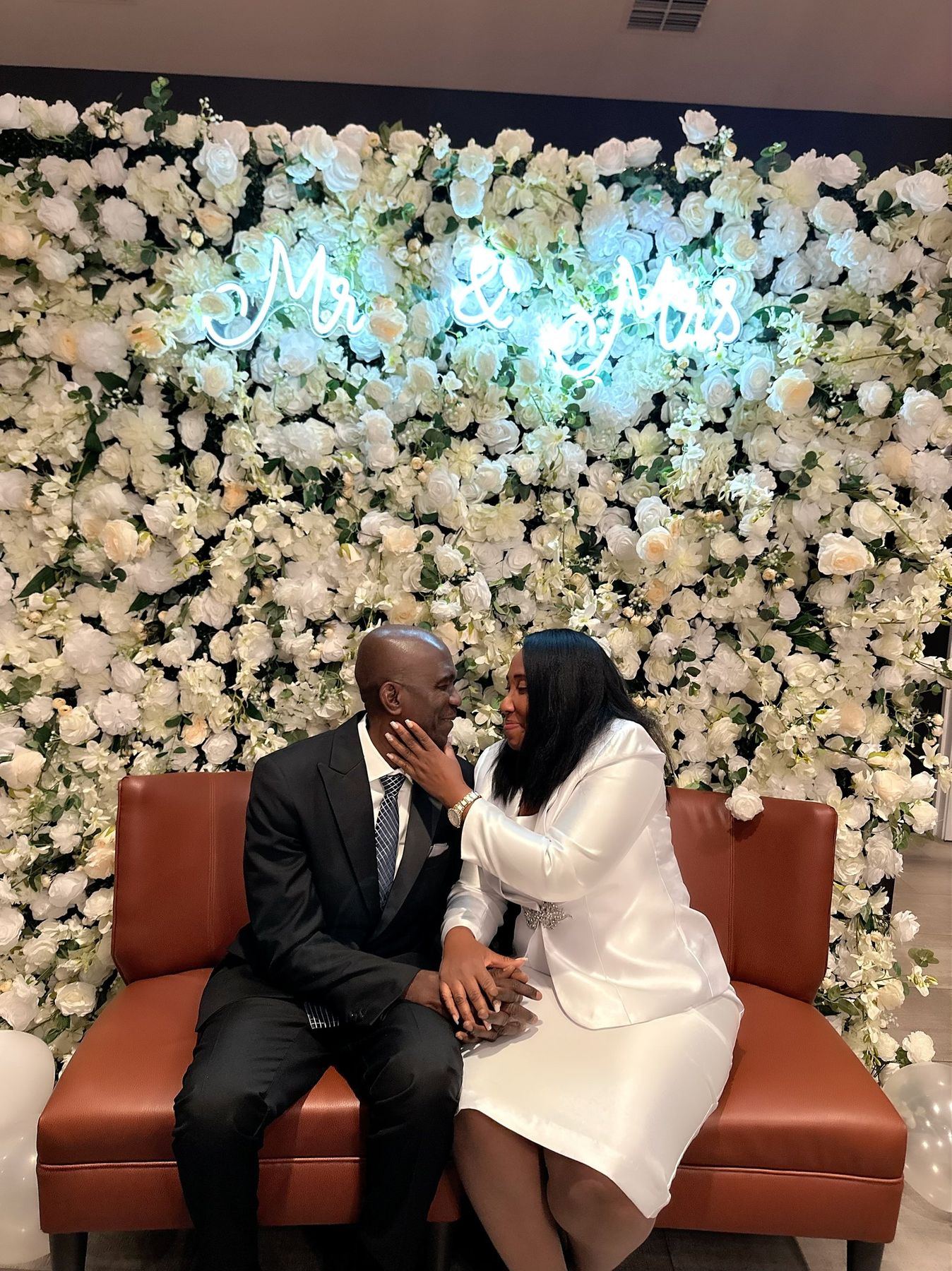 Couple in front of the Donna Champagne flower wall with a Mr & Mrs LED sign at a Tampa Bay wedding